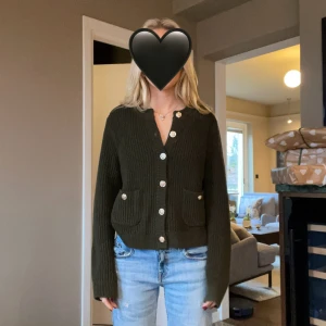 Mörkgrön stickad kofta från H&M - Snygg mörkgrön stickad kofta från H&M med grov ribbad struktur och  knappar framtill. 