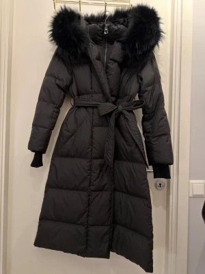 Svart lång dunjacka med päls - Oanvänd vinterjacka i - nyskick storlek M men passar även en som vanligtvis har storlek S.