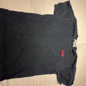 Svart Comme des Garçons Play t-shirt XL - Svart t-shirt från Comme des Garçons Play i storlek XL men garanterar att de känns som en L. Klassisk modell med rund hals och korta ärmar. På bröstet finns två broderade hjärtan i rött