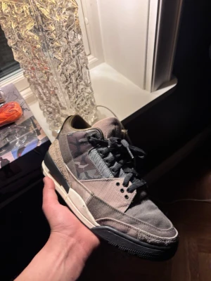 Nike Jordan 3 Camo sneakers - Unika Nike Jordan 3 sneakers med camouflagemönster i mörka toner av grått, svart och beige. Skorna har snörning, rund tå och platt sula. Materialmix av mocka och textil, med orange detaljer på insidan. Perfekt för dig som vill sticka ut med en cool streetstil. Dom går för runt 5000 - 7000kr helt nya! Så skulle säga att priset är ganska värt.