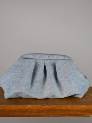 Clutchväska  - Clutchväska, perfekt till fest och vardag.  Denna väskan är gjord av ljus blå jeans på utsidan och grått möbeltyg på insidan.  Innuti finns en ficka där du kan lägga småsaker och du stänger enkelt med clutch ramen.  Clutchram ca 18cm bredd, bredd nertill ca 25cm, höjd ca 15cm. 