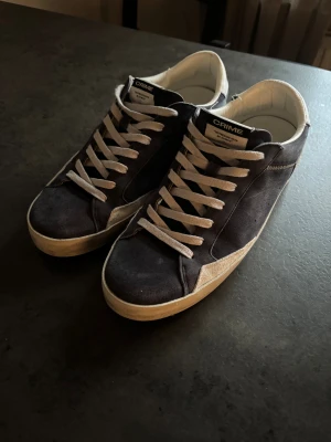 Mörkblå sneakers från Crime London - Snygga mörkblå sneakers från Crime London med vita detaljer och snörning. Ovandelen är i mocka och skinn, med vit hälkappa och robust vit sula. Klassisk låg modell med rund tå och coola kontrastsömmar. Perfekta för dig som gillar streetstyle och vill ha något unikt.