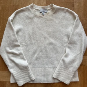 Vit stickad tröja från & Other Stories - Supermysig vit stickad tröja från & Other Stories med rund hals och breda ribbade muddar vid ärmslut och nederkant. Perfekt för kyliga dagar och enkel att matcha med jeans eller kjol.