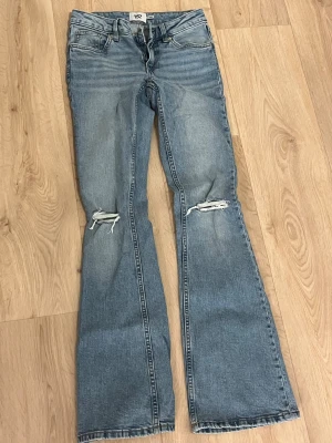 Blå bootcut jeans med slitna knän - Snygga blå bootcut jeans från 157 med slitna detaljer på båda knäna. Jeansen är helt oanvända då jag inte gillar midjehöjden. Skulle säga att jeansen är mid waist och inte low. Pris kan diskuteras. Köparen står för frakt