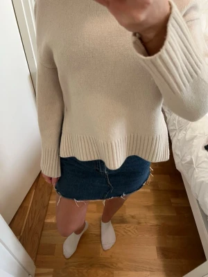 Blå jeanskjol med rå kant - Trendig blå jeanskjol med rå, fransig kant nertill. Klassisk femficksmodell och kort passform som ger en avslappnad och cool vibe. Perfekt att matcha med stickad tröja eller t-shirt för en casual look.