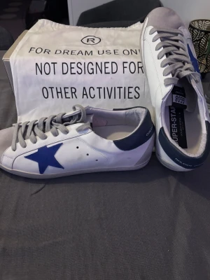 Golden Goose vita sneakers med blå stjärna - Golden Goose sneakers i vitt läder med blå stjärna. Kommer med orginal skolåda och dustbag! Pris kan diskuteras🤝 Hör av dig vid frågor!