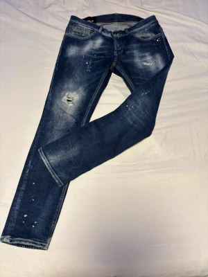 Dondup jeans - Snygga mörkblå jeans med slitningar och blekta partier, samt små färgstänk för en cool, använd look. Jeansen har klassisk femficksmodell och raka ben. Perfekta för dig som gillar streetstyle och en avslappnad vibe.