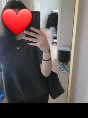 Mörkgrå stickad  t-shirt - En enkel mörkgrå t-shirt med rund hals och korta ärmar. T-shirten har en avslappnad passform och är tillverkad i mjukt bomullsmaterial. Perfekt till jeans eller shorts för en clean och stilren look.