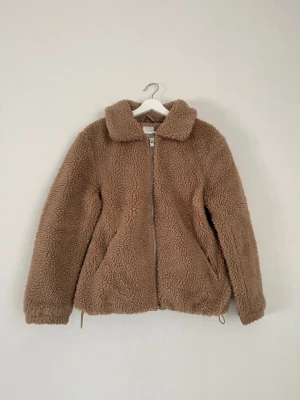 Teddyjacka - H&M - S - Fin brun/beige teddyjacka från H&M, storlek S. Dragkedja och dragsko i nederkanten. Tecken på användning på strukturen enligt bilder, men annars fint skick!