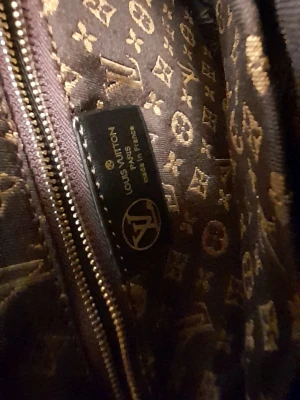 Louis Vuitton monogram handväska - Säljer en snygg handväska från Louis Vuitton med klassiskt monogrammönster i brunt och beige. Väskan har både handtag och axelremmar samt guldfärgade detaljer. Tillverkad i canvas med läderdetaljer. Perfekt för dig som gillar lyxiga accessoarer.