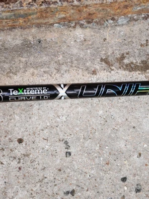 Unihoc innebandyklubba TeXtreme - Säljer en svart innebandyklubba från Unihoc med TeXtreme carbon fibre technology och Curve 1.0°. Klubban har vita och holografiska detaljer samt vitt grepp. Perfekt för dig som vill ha lätt och avancerad klubba.    Ett vitt unilite blad i (PPti plast).