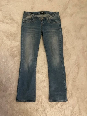 Blå bootcut jeans från LTB - Snygga blå bootcut jeans från LTB med klassisk femficksdesign och diskreta slitningar framtill. Jeansen har normal midja och lätt utsvängda ben. Perfekta för en avslappnad och trendig look. 
