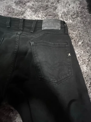 Svarta jeans från Replay - Snygga svarta jeans från Replay med klassisk femficksdesign och diskret logga på fickan. Jeansen har raka ben och bälteshällor, perfekta för en stilren look. Materialet är denim i bomullsblandning.