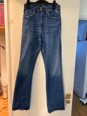 Blå jeans från Replay strl: 25/30 - Säljer ett par snygga blå jeans från Replay med klassisk femficksdesign och rå, fransad kant nedtill. Jeansen har en rak passform och är tillverkade i mjukt denimtyg med lätt tvättad look. Perfekt för dig som gillar en avslappnad stil.
