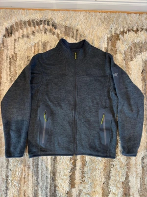 Mörkblå fleecejacka från Arc'teryx - Mörkblå fleecejacka från Arc'teryx med hel dragkedja och två fickor med blå detaljer och mörkgröna zippar. Jackan har lång ärm och diskret logga på ena ärmen. Perfekt för lager-på-lager och outdoor. Mjuk och skön känsla i materialet. Säljer den då jag inte använder den längre! Perfekt för skidåkning eller bara kyligare dagar ute😁Nypris på denna ligger på drygt 2200 kr och jag säljer den för 1200! Bara att skriva om de finns några frågor eller om fler bilder behövs🤗