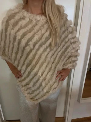 Beige randig poncho - Säljer en fluffig beige poncho med breda diagonala ränder. Västen är oversized och har en mysig känsla💓