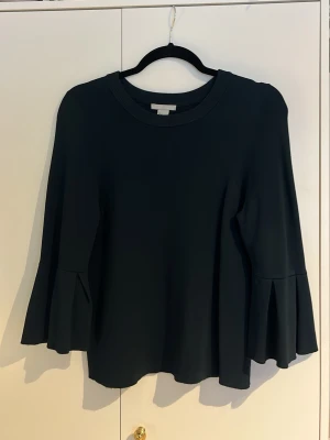 Tröja med utsvängda armar - Säljer tröja från H&M i storlek S. Toppen har utsvängda armar som ger en snygg och trendig look. Enkel att matcha med jeans eller kjol. Den är mörk i färgen och går mot mörkgrön/mörkblå men upplevs som svart. 