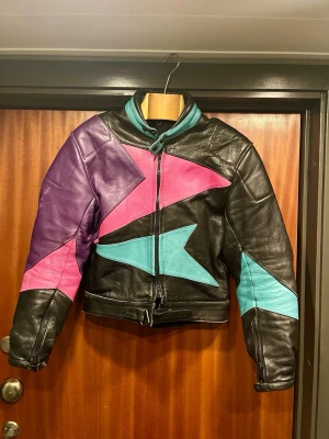 Rejäl motorcykeljacka med grafisk design - Skitcool läderjacka som skulle överleva nästan vad som helst, tjockt och ordentligt läder. Inga större skador men lite lagom sleten som vintage-läder brukar bli. Finns ett fack för ryggskydd. Bäst på någon 46-48.