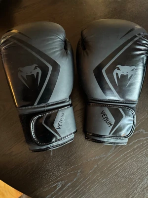Svart boxningsset  Venum/Adidas - Bokstavligen använt 1 gång, syns på bilden under skorna . Hjälmen är aldrig använd . CONTENDER 2.0 BOXING GLOVES	 VENUM	 BLACK/BLACK	 14 OZ : 370kr (ord.pris 600 kr). Adidas Boxing Headgear 350 kr ( ord.pris 500 kr).  Nordcore Boxing Shoes Core Bout strl.43 (motsvarar strl 42 i vanliga skor) 420 kr (ord.pris 600 kr ).