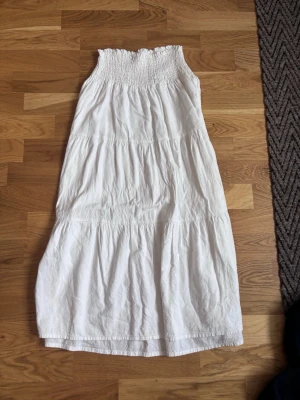 Vit långkjol - Superskön vit långkjol med smock upptill som ger en snygg och bekväm passform. Kjolen har flera volanger, från h&m i storlek 158/164