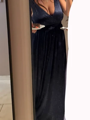 Marinblå glittrig långklänning - Säljer en marinblå balklänning med glittriga detaljer och v-ringad hals. Klänningen har breda axelband och ett markerat midjeband som ger en snygg siluett. Perfekt för balen 2026!🤍bara använd en gång