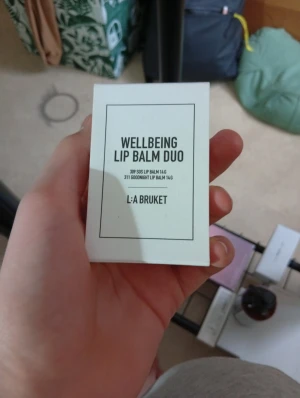 L:A Bruket Wellbeing Lip Balm Duo - Säljer ett duo-pack med läppbalsam från L:A Bruket. Ena stiftet är blått och heter SOS Lip Balm med pepparmint, det andra är svart och heter Goodnight Lip Balm med apelsinblomma. Båda kommer i praktiska plastförpackningar på 14 g vardera.