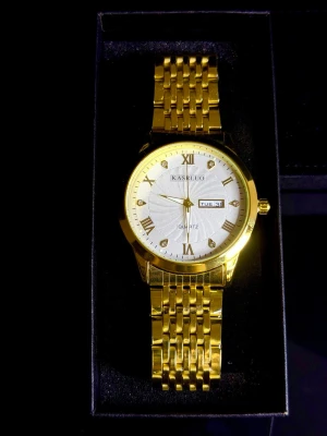 Kasrluo Imperium *Helt ny* - Kasrluo Imperium, helt ny och oanvänd. Elegant, romersk & tidlös herrklocka med guldfärgad boett samt vit urtavla som ger ett klassiskt och lyxigt uttryck. Perfekt för dig som vill ha en stilren klocka som funkar både till vardag och fest.