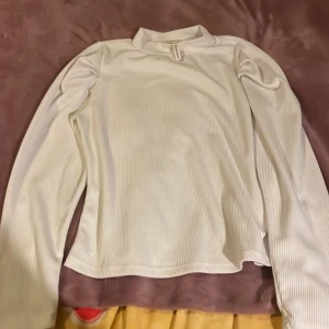 Vit ribbad polotopp från Object - Säljer en vit ribbad polotopp från Object i storlek L. Toppen har lång ärm och en högre krage som ger en clean look. Materialet är mjukt och stretchigt, perfekt för lager på lager. Enkel och stilren design som funkar till mycket.