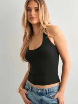 Svart croppad linnetopp - Snygg svart croppad linnetopp med rundad halsringning och smala axelband. Perfekt till jeans eller kjol för en enkel och stilren look. Materialet känns mjukt och följsamt mot kroppen. Strl: S från NELLY