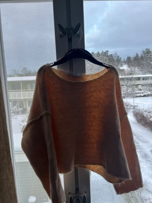 Beige croppad stickad tröja från Zara - Säljer en beige croppad stickad tröja från Zara med bred halsringning och långa ärmar. Tröjan har en loose passform och synliga sömmar vid axlarna för en chill vibe. Perfekt för lager-på-lager under kalla dagar.
