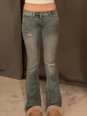 Lågmidjade bootcut jeans - Säljer ett par lågmidjade bootcut jeans med egen gjorda hål💕