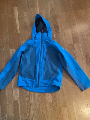 Skaljacka - Tunn blå skaljacka i storlek 158/164 från North Bend. Vattentålig och i bra skick. Finns några skavanker/slitage som syns på bilderna men inget som påverkar jackans funktion och utseende överlag tycker jag. Säljes då den inte passar längre. Djur och rökfritt hem. 