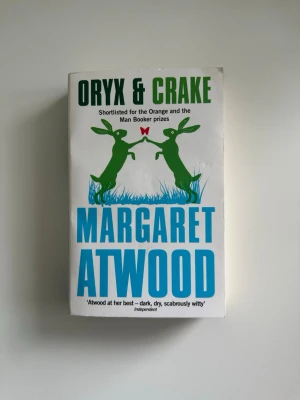 Oryx & Crake av Margaret Atwood - En prisnominerad roman av Margaret Atwood som bjuder på en fantasifull och gripande berättelse. Perfekt för dig som gillar äventyr, oväntade karaktärer och vill utforska en unik värld. Boken har hyllats för sin mörka humor och sitt djärva berättande. En av de bästa böcker jag läst! Gott skick!  ISBN 978-0-349-00406-8 