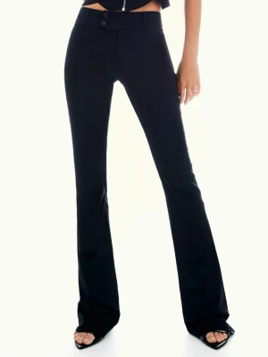 Bershka - Flared Bengaline - tygbyxor  - Säljer ett par svarta bootcut-byxor från Bershka i storlek 36. Byxorna har hög midja, två knappar framtill och är tillverkade i ett mjukt och stretchigt material som sitter snyggt. Perfekta för dig som gillar en clean och trendig look.