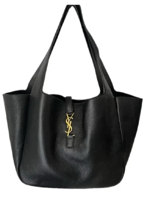Svart shoppingväska från Saint Laurent - Stilren svart shoppingväska från Saint Laurent i skinn med klassisk YSL-logga i guld framtill. Väskan har rymlig form och breda axelband som gör den enkel att bära. Perfekt för dig som vill ha både lyx och funktion i vardagen.