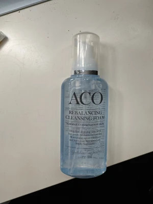ACO Rebalancing Cleansing Foam - ACO Rebalancing Cleansing Foam är en ansiktsrengöring i blå plastflaska med pump. Skummet är anpassat för normal och kombinerad hud, innehåller AHA-syra som exfolierar och återfuktar huden. Mild doft och praktisk för daglig rengöring.