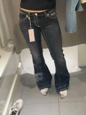 Svarta bootcut jeans Gina Tricot - Säljer ett par svarta bootcut jeans från Gina Tricot med kontrasterande vita sömmar och snygga detaljer på bakfickorna. Jeansen har låg midja och klassisk femficksdesign. Materialet är jeans och passformen är loose nertill för en riktigt retro vibe. Använd en gång och priset kan diskuteras 