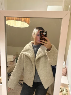 Beige teddyjacka med stor krage - Supermjuk och fluffig teddyjacka i beige med oversized känsla och stor krage. Jackan har lång ärm och är tillverkad i ett mysigt teddy-material som håller dig varm under kyliga dagar. Perfekt för dig som gillar en trendig och avslappnad stil.