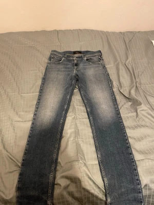 Replay mörk blå slim fit  - Säljer ett par snygga mörkblå jeans från Replay med klassisk femficksdesign och slim ben. Jeansen har slitna detaljer och snygg tvätt, samt Replay-logga på bakfickan. Perfekta för en avslappnad stil.