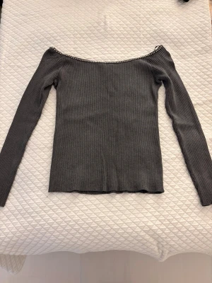 Grå ribbad offshoulder topp med pärlor - En grå ribbad offshoulder topp. Toppen har pärlor längs den vida urringningen. 