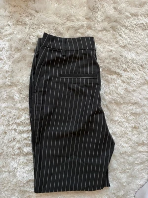 Randiga kostymbyxor  - Mörkgrå/vit randiga kostymbyxor. Använda 1 gång. Mycket bra skick! 