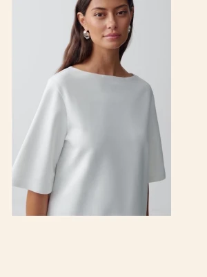 Vit minimalistisk blus med vid ärm - Säljer en stilren vit blus med rak passform och vida, korta ärmar. Blusen har en enkel och modern design med rundad halsringning och är tillverkad i ett slätt tyg som ger en clean look. Perfekt för dig som gillar minimalistisk stil.