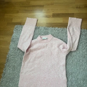 Ljusrosa stickad tröja  - Supermysig ljusrosa stickad tröja från Kappahl med breda ribbade muddar vid ärmslut och nederkant. de är slitsade där nere vid nederkant. Rund hals och långärmad modell.