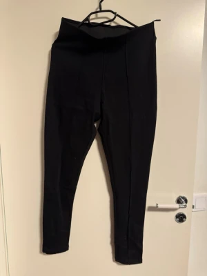 Svarta högmidjade leggings från Dunnes  - Säljer ett par svarta leggings med hög midja och smal passform. Byxorna har en enkel och stilren design utan synliga detaljer eller fickor. Perfekta att matcha med oversized tröjor eller hoodies.