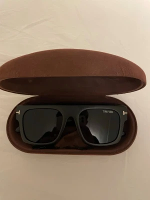 Tom Ford solglasögon  - Snygg svart solglasögon från Tom Ford med klassisk rak passform och diskreta detaljer. De har en stilren design. Perfekt för lager-på-lager och funkar till många olika outfits.