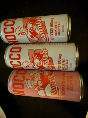 Nocco Skumtomte energidryck 3-pack - Tre burkar Nocco Skumtomte energidryck med juligt motiv. Burkarna är 330 ml, har röd och vit design och innehåller 180 mg koffein. Drycken är sockerfri och kolsyrad, perfekt för dig som gillar energidrycker med godissmak.