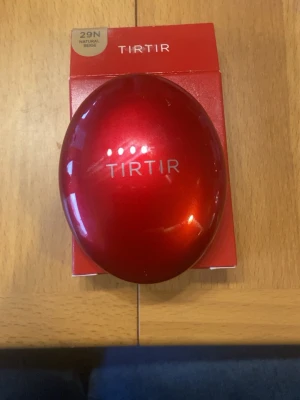 Mini TIRTIR Mask Fit Red Cushion 29N - TIRTIR Mask Fit Red Cushion i färgen 29N Natural Beige. Kommer i en snygg, rund röd metallisk dosa med spegel och foundation i cushion-format. Perfekt för att få en jämn och naturlig bas med smidig applicering. Innehåller 4,5g produkt och är tillverkad i Korea.