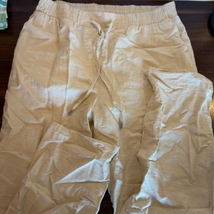 Beiga linnebyxor från LCW Modest - Säljer ett par beiga linnebyxor från LCW Modest med avslappnad passform och resår i midjan. Byxorna har snörning framtill och är perfekta för varma dagar. Materialet är lätt och luftigt linne som ger en skön känsla.