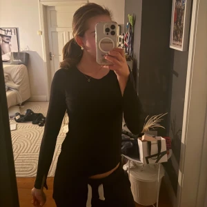 Svart långärmad tröja från 157 - En svart långärmad tröja från 157 med enkel och clean design. Tröjan har rund halsringning och är tillverkad i ett mjukt, stretchigt material som sitter snyggt på kroppen. Perfekt basplagg att styla med jeans eller kjol.