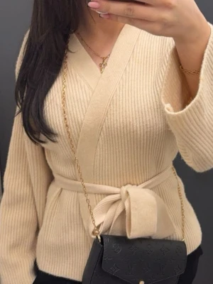 Beige ribbad omlottkofta med knyt - Säljer en beige ribbad omlottkofta med knyt i midjan. Koftan har lång ärm och en mjuk, stickad känsla som gör den perfekt för lager på lager. Enkel men ändå chic design som passar till det mesta.